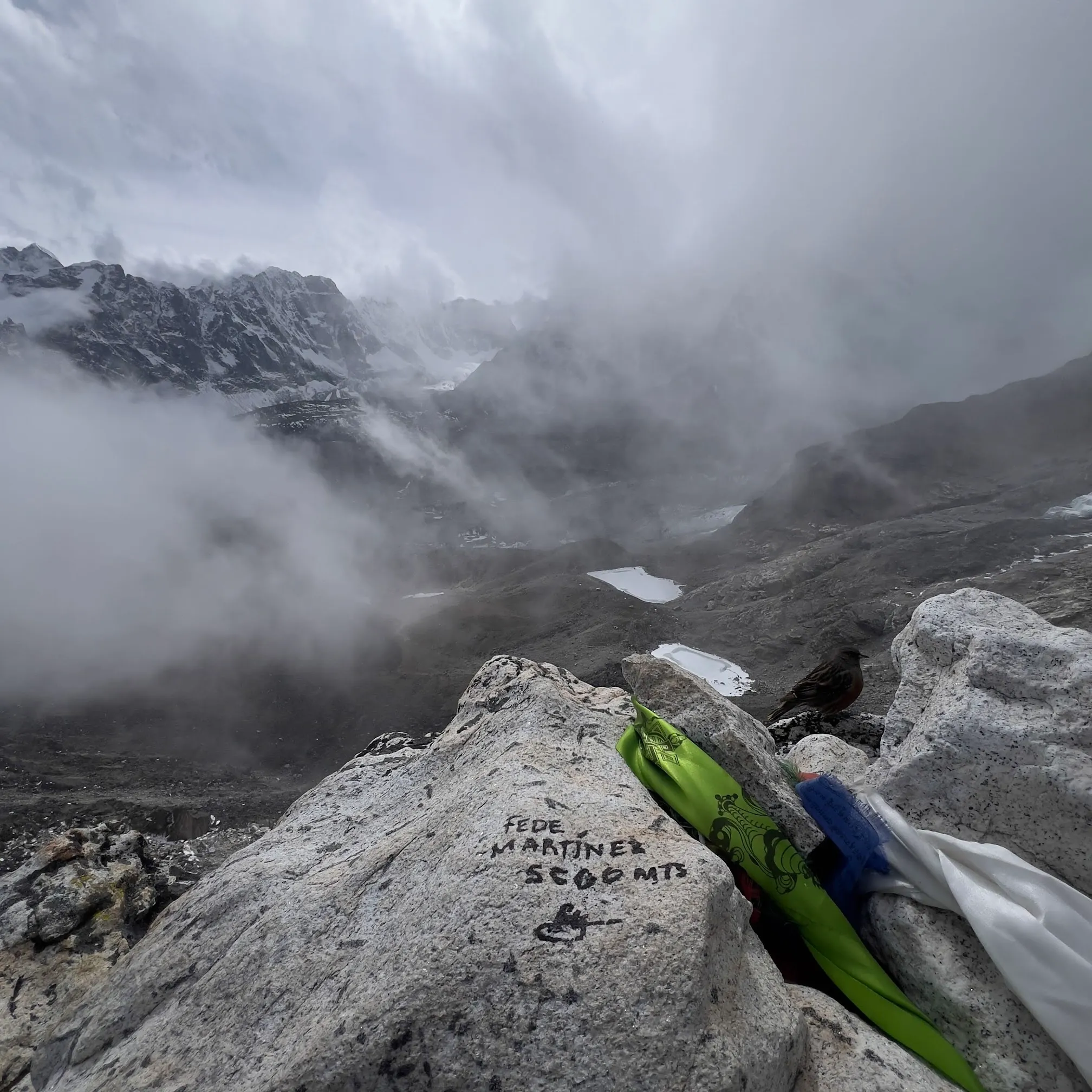 Granite rock at Kala Patthar signed “Fede Martínez, 5600 mts”, clouds rolling over the glacier below