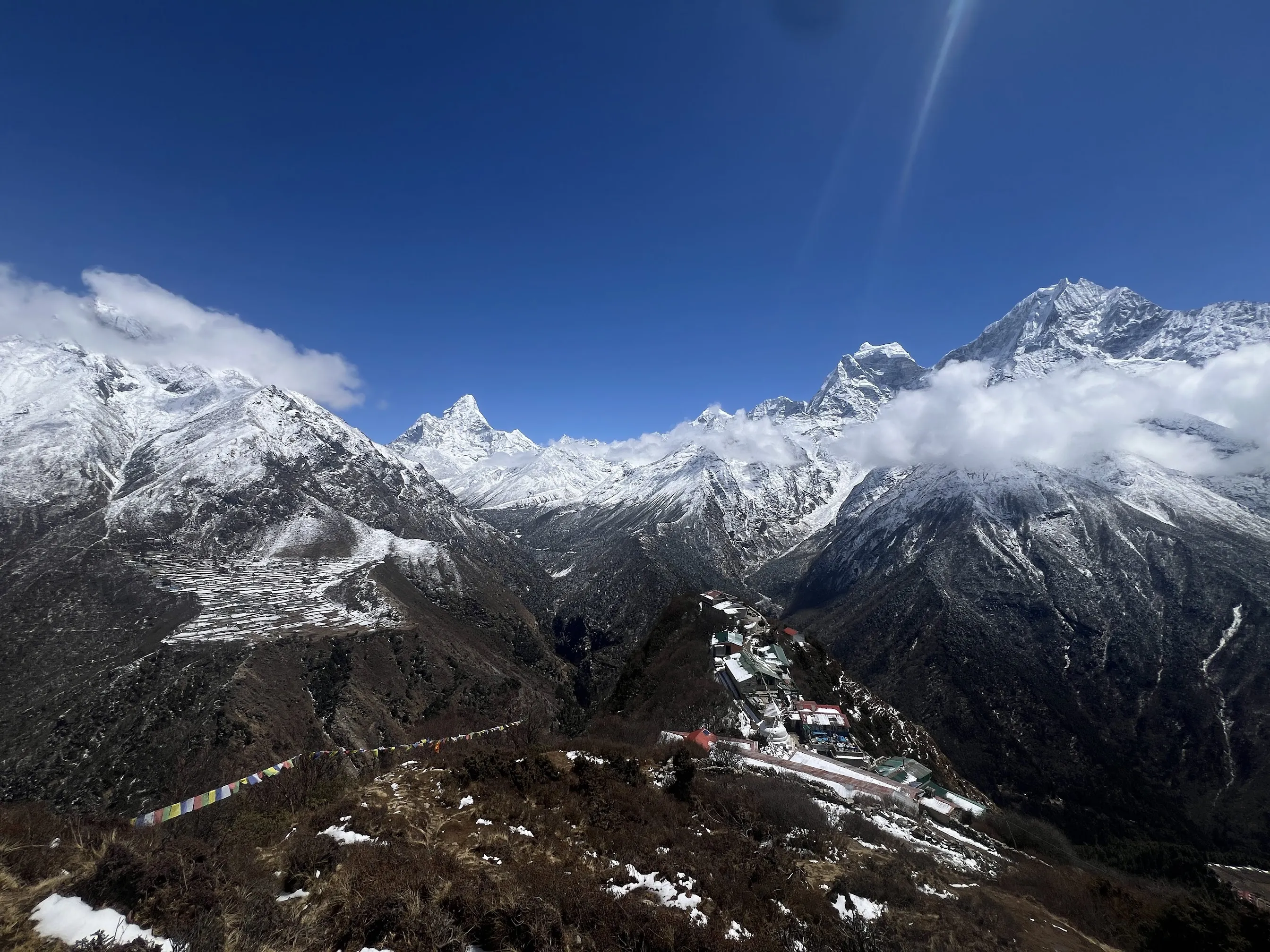 Snow-capped Khumbu peaks under a deep blue sky, a monastery on the ridge below